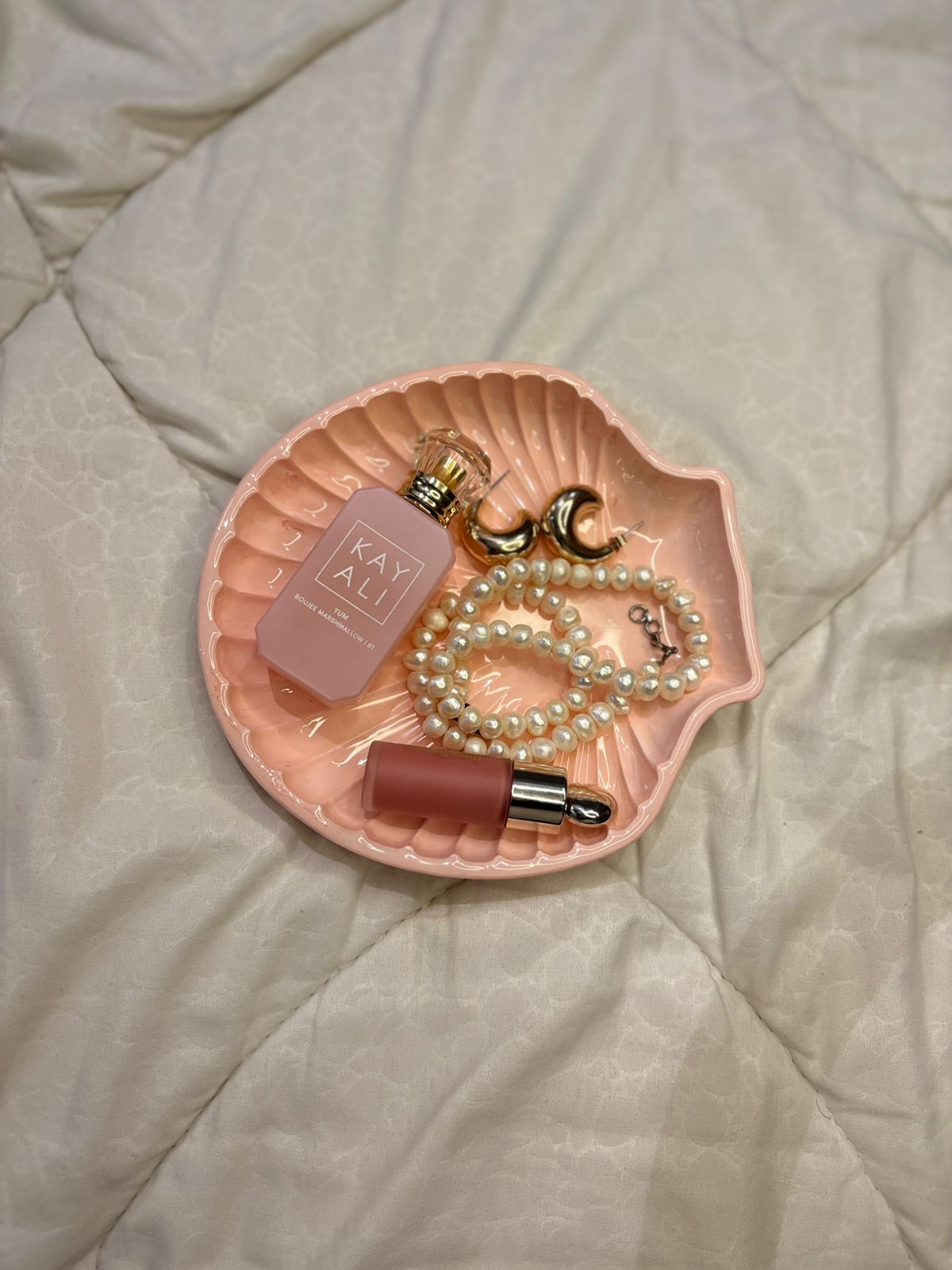 Pink shell-shaped dish with perfume, lip gloss, and jewelry 